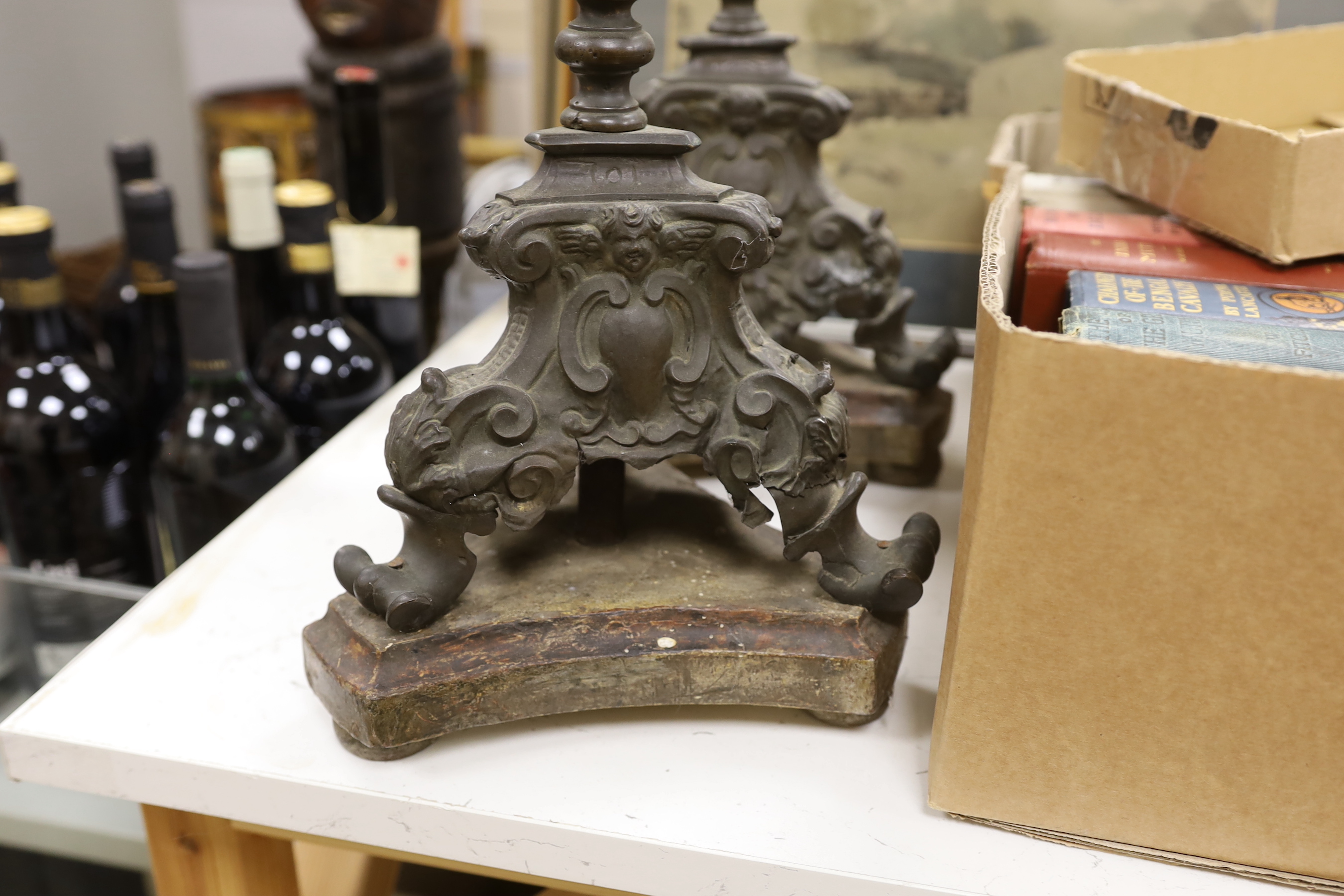 A pair of late 17th / 18th century Italian altar pricket candlesticks of sheet brass, each with foliate knopped baluster stem with shell, putto mask and cartouche bases, above wooded bases, 69cm